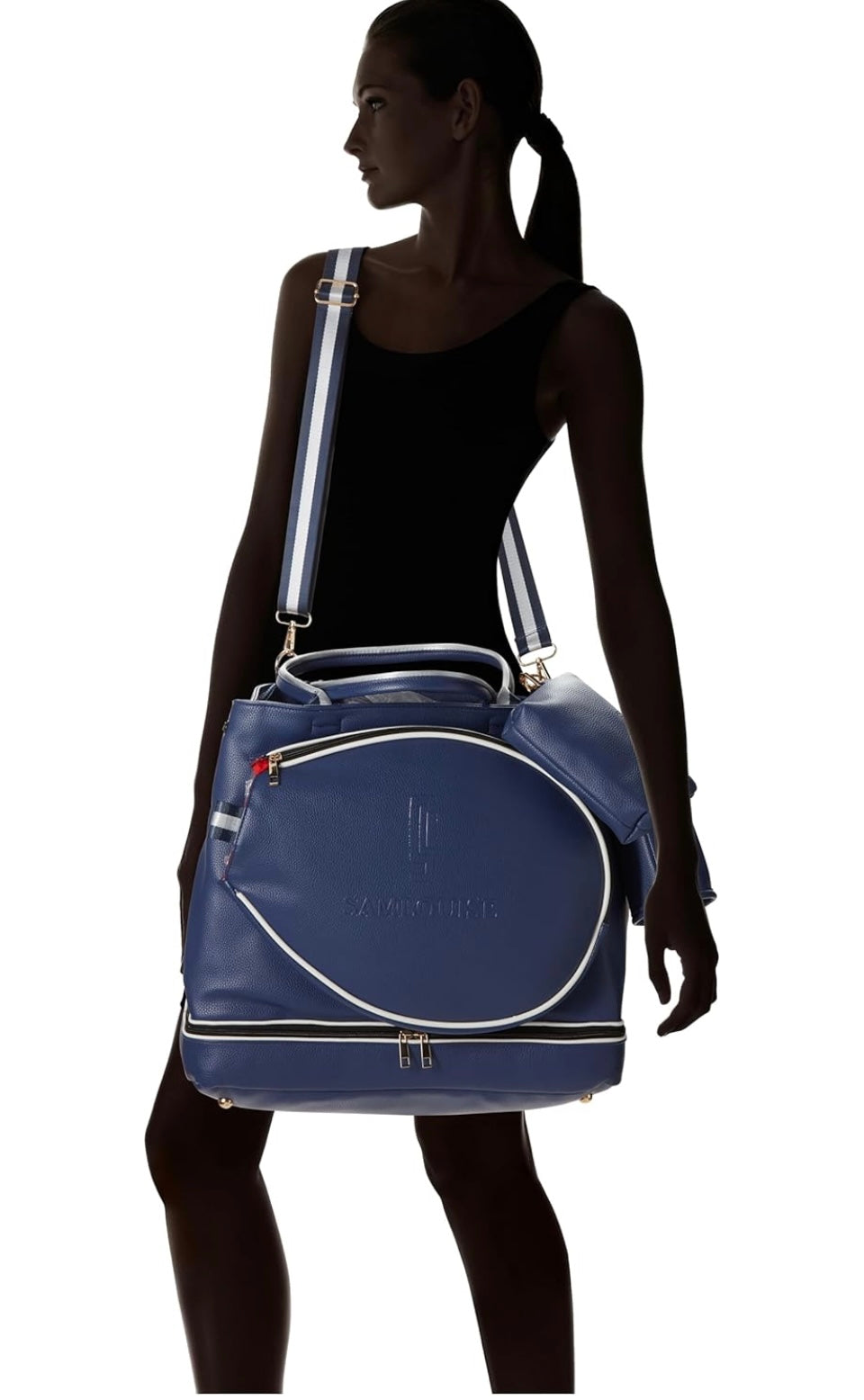 The SamLouise London 77 Tennis Tote from SamLouise is a chic sports tote bag in blue with white accents and a detachable strap. It includes a zippered bottom compartment, an insulated bottle holder, and a cylindrical pouch on the side.