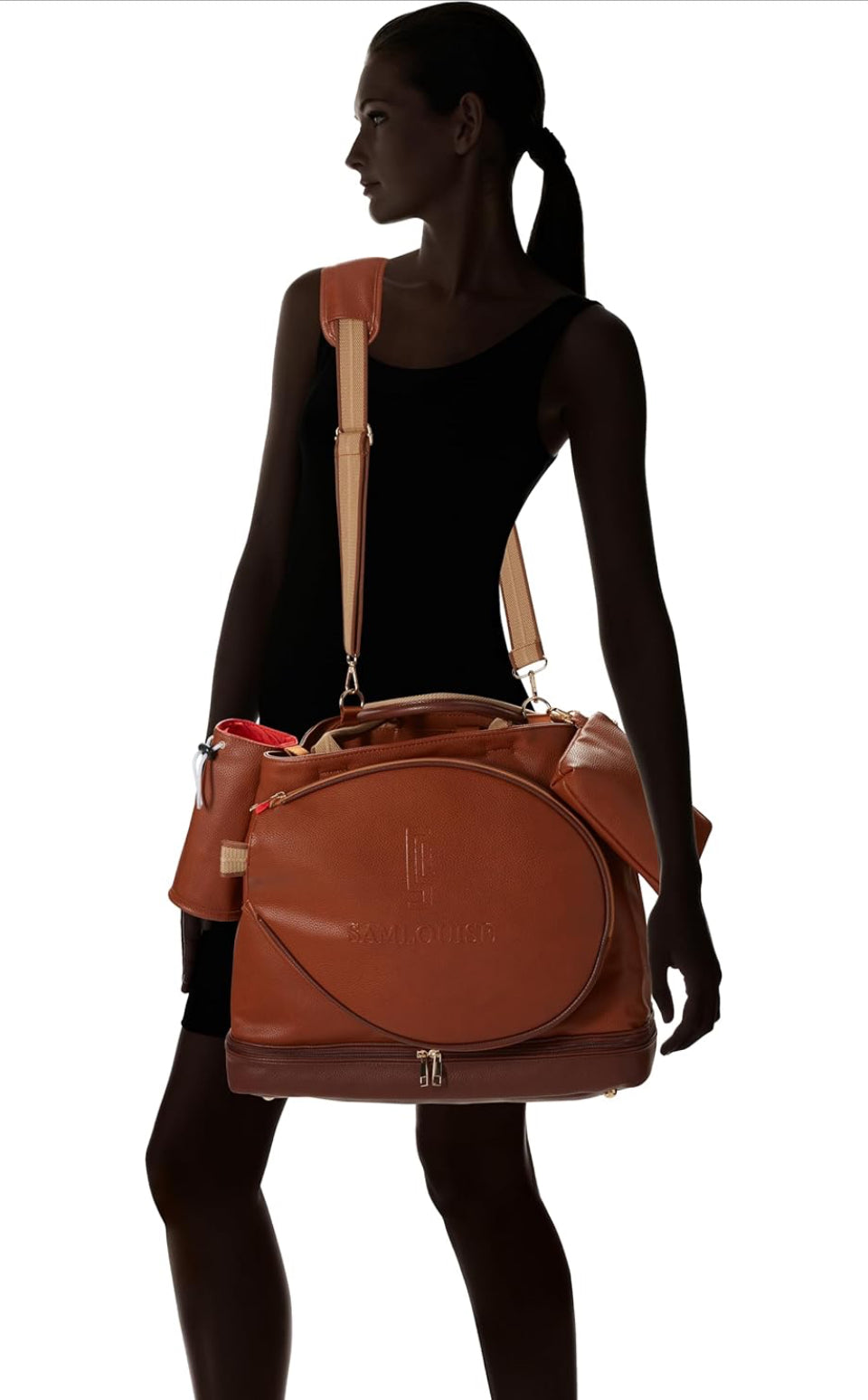 The SamLouise London 77 Tennis Tote from SamLouise is a chic sports tote bag in blue with white accents and a detachable strap. It includes a zippered bottom compartment, an insulated bottle holder, and a cylindrical pouch on the side.